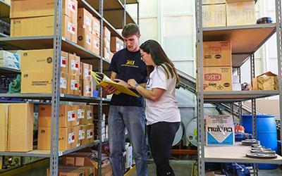 Two students consult a clipboard in an industrial distribution lab